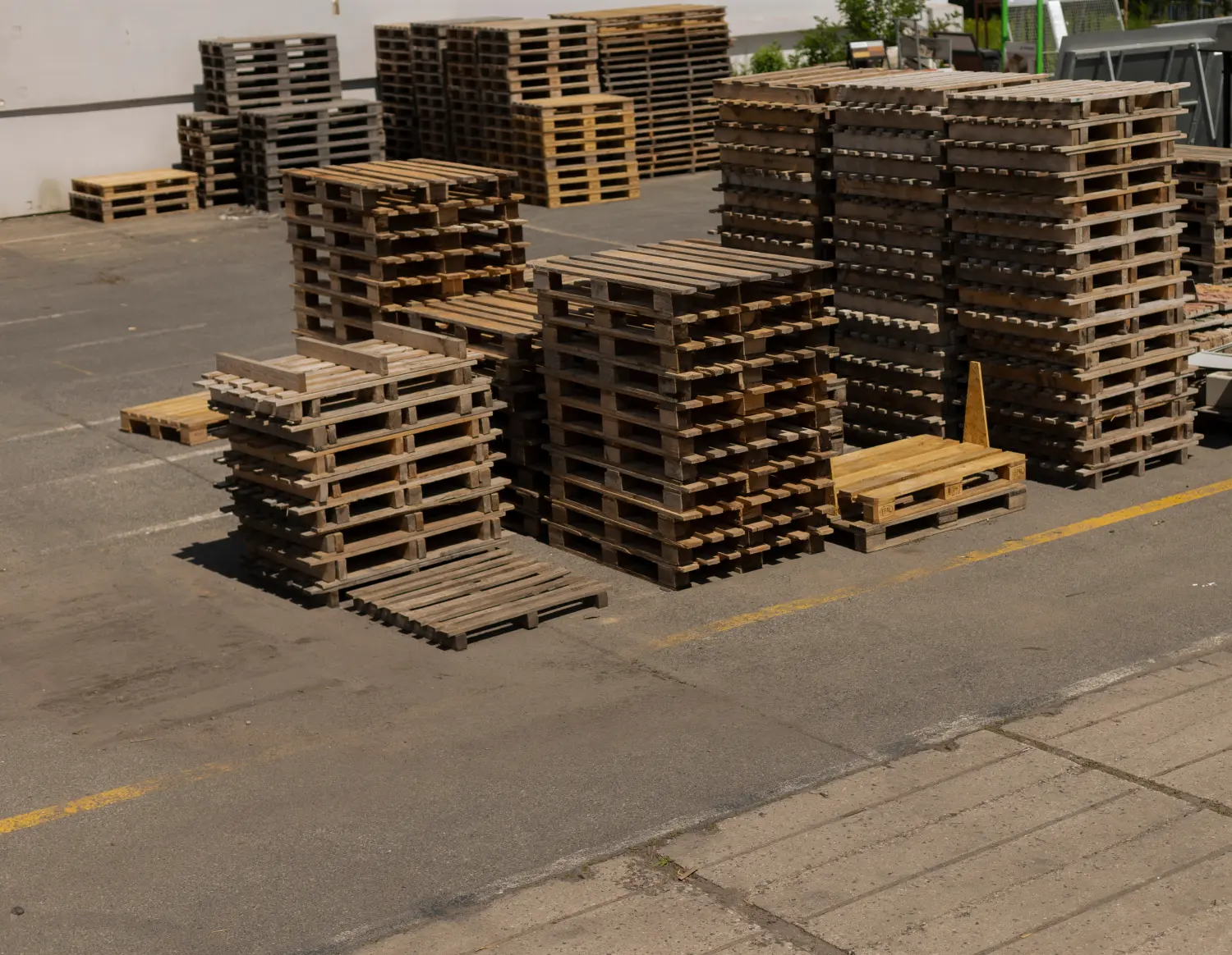 In einer geräumigen Lagerhalle befindet sich eine große Sammlung ordentlich gestapelter Holzpaletten.
